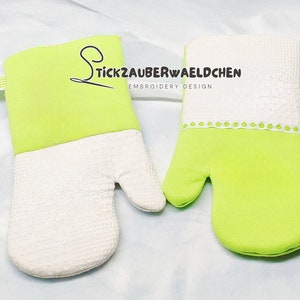 Könnte beinhalten: Zwei grüne und weiße Ofenhandschuhe mit einer weißen bestickten Bordüre und dem Text "Stickzauberwaeldchen Embroidery Design".