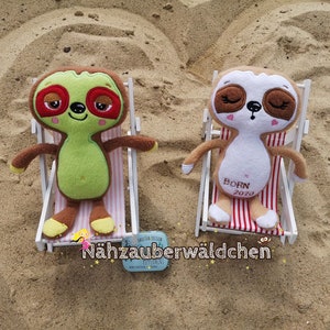 May include: Two plush sloth toys, one green and one brown, are sitting in white beach chairs. The green sloth has red eyes and a smile, while the brown sloth has closed eyes and the text "Born 2020" embroidered on its chest.