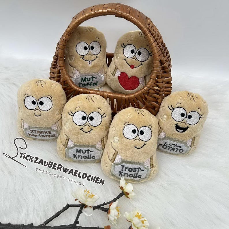 May include: A selection of plush potato-shaped toys with embroidered faces and small signs. Some are in a woven basket. The signs have German text. The toys are beige with black and white details.
