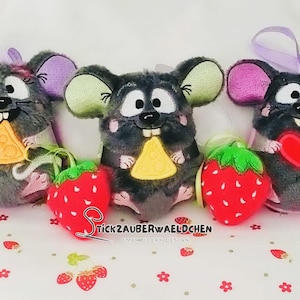 Op de afbeelding: Drie pluche muisornamenten met grote oren, met een stukje kaas of een rood hart. Elke muis heeft een aardbeienornament. De muizen zijn grijs met roze en groene accenten. De tekst "TickZauberwaeldchen" is zichtbaar.