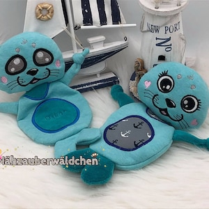 May include: Two turquoise blue plush seal toys with embroidered faces and details. One seal has an anchor and the other has the word "Okay" embroidered on its belly.