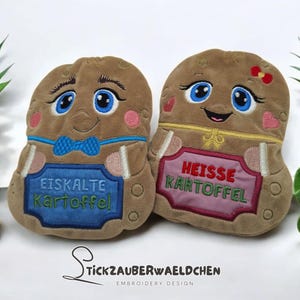 Può includere: Due giocattoli a forma di patata di peluche con facce sorridenti, occhi blu e guance rosee. Uno ha un papillon blu e un cartello blu che dice "Eiskalte Kartoffel". L'altro ha un fiocco rosso e un cartello rosa che dice "Heisse Kartoffel."