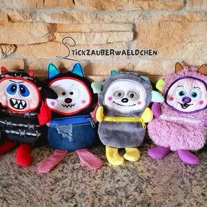 May include: Six plush toys with different colorful designs and embroidered faces. The toys are all in a row on a stone surface. The toys are all about 10 inches tall.