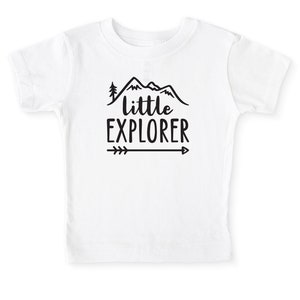 White short sleeve toddler crew neck tee with black LITTLE EXPLORER hand drawn rocky mountain range, pine tree and arrow design printed on the front, laying flat on white background