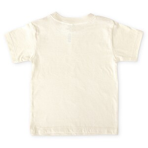 Back view of short sleeve natural white toddler crew neck tee laying flat on white background