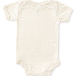 Back view of natural cream colored short sleeve baby bodysuit laying flat on white background