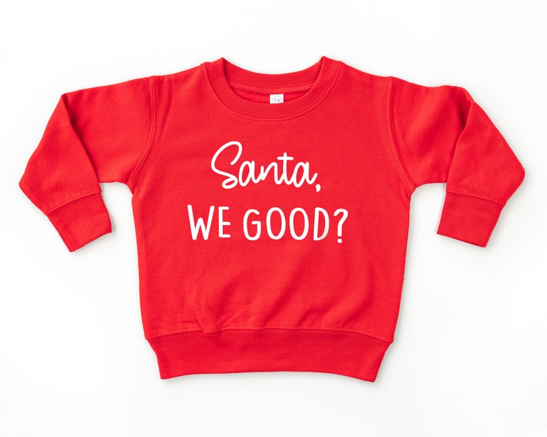 Red long sleeve crew neck toddler sweatshirt with white Santa, WE GOOD? graphic print, laying flat on white background