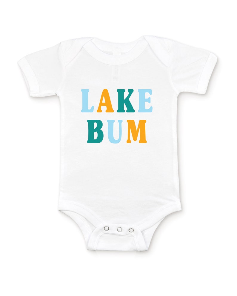 White short sleeve baby bodysuit with alternating light blue, mustard yellow and teal blue LAKE BUM text print on front, laying flat on white background