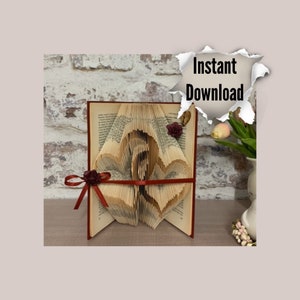May include: A book art sculpture with two hearts folded from the pages. The book is bound in red and has a red ribbon tied around it. The sculpture is decorated with small red flowers.