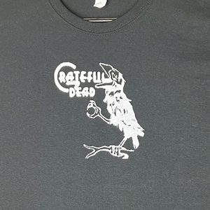 May include: A dark gray t-shirt with a white graphic of a crow with the text "Grateful Dead" on it.