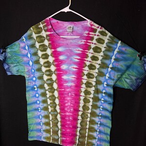 May include: A tie-dye t-shirt with a pink, blue and green colour scheme. The shirt has a v-neck and short sleeves.