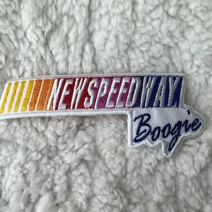 May include: White embroidered patch with the text "NEW SPEEDWAY Boogie" in a rainbow colour scheme. The patch has a white background with a rainbow stripe design.
