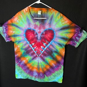 May include: A tie-dye t-shirt with a large red heart in the centre. The shirt is a mix of blue, green, orange, and purple.