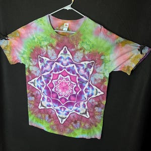May include: A tie-dye t-shirt featuring a colourful mandala design in shades of pink, purple, green, and blue. The mandala is centred on the shirt and has a starburst pattern.