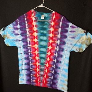 May include: A tie-dye t-shirt with a vertical pattern of red, blue, and purple. The shirt has a crew neck and short sleeves.
