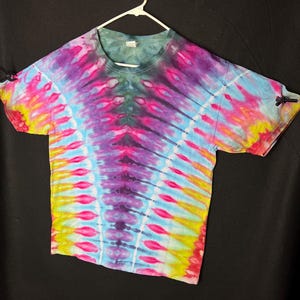 May include: A tie-dye t-shirt with a vibrant colour scheme, featuring shades of pink, blue, yellow, and purple. The shirt has a classic crew neck and short sleeves.