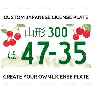 Puede incluir: Una placa de matr&iacute;cula japonesa blanca con texto y n&uacute;meros verdes. La placa dice "山形300" y "47-35". La placa tambi&eacute;n tiene un car&aacute;cter verde "ほ" y un dise&ntilde;o de flor de cerezo.