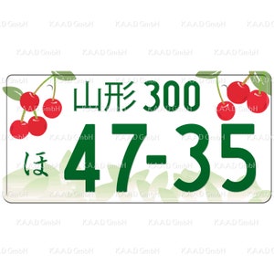 Puede incluir: Un letrero rectangular blanco con texto y n&uacute;meros verdes. El letrero dice "山形 300 ほ 47-35". El letrero est&aacute; decorado con cerezas rojas y hojas verdes.