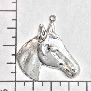 Puede incluir: Encanto de cabeza de caballo de metal plateado con un bucle en la parte superior para sujetarlo a joyas o manualidades. El encanto mide aproximadamente 2,5 cm de alto.