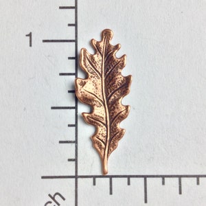 May include: A single copper-coloured leaf charm with a detailed oak leaf design. The leaf is approximately 2.5 cm in length.