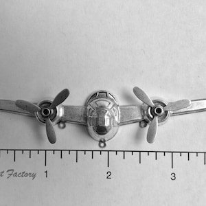 May include: Silver airplane charm with three propellers. The charm is approximately 5 cm long.