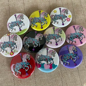 May include: Nine colorful round buttons with a carousel horse design. Each button features a different color background and a different horse design. The horses are all in a similar pose, with their heads turned to the side and their legs raised in the air. The buttons are perfect for adding a touch of whimsy to any project.