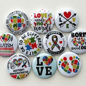 May include: Ten 1-inch button pins with various designs related to autism awareness. The designs include puzzle pieces, hearts, ribbons, and footprints. The text on the buttons includes phrases like "Autism Awareness", "Love needs no words", "It's OK to be different", and "Born to stand out".