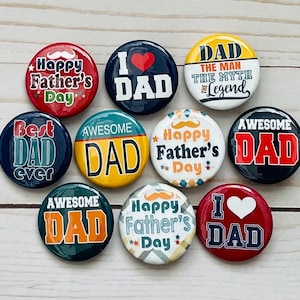 May include: A collection of round pinback buttons with various designs and text. The buttons feature phrases like "Happy Father's Day," "I ❤️ DAD," and "Awesome Dad." Colors include red, blue, yellow, and white. Some buttons have mustache graphics.