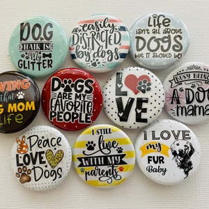 May include: Ten round buttons with various dog-themed sayings. The buttons are white with black text and various colored accents. Some of the sayings include "Dog Hair is My Glitter", "Dogs are My Favorite People", "I Still Live With My Parents", and "I Love My Fur Baby".