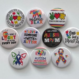 May include: Ten round button pins with various autism awareness designs. The designs include a light bulb, a puzzle piece, a butterfly, a bear, and a ribbon. The text on the buttons includes "Peace Love Autism", "I Love Someone With Autism", "I Am A Proud Autism Mom", "One Lucky Mama", "Shine A Light On Autism Every Day", and "Autism Awareness Accept Understand Love".