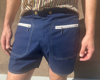 Peut inclure: Short en jean bleu marine avec des bordures blanches et des poches zippées. Le short a une jambe droite et une coupe décontractée.