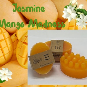 May include: Two bars of handmade soap with a mango scent and jasmine essential oil. The soap bars are yellow and have a label that says "Jasmine Mango Madness Handmade Soap 4-5oz". The soap bars are surrounded by mango slices.