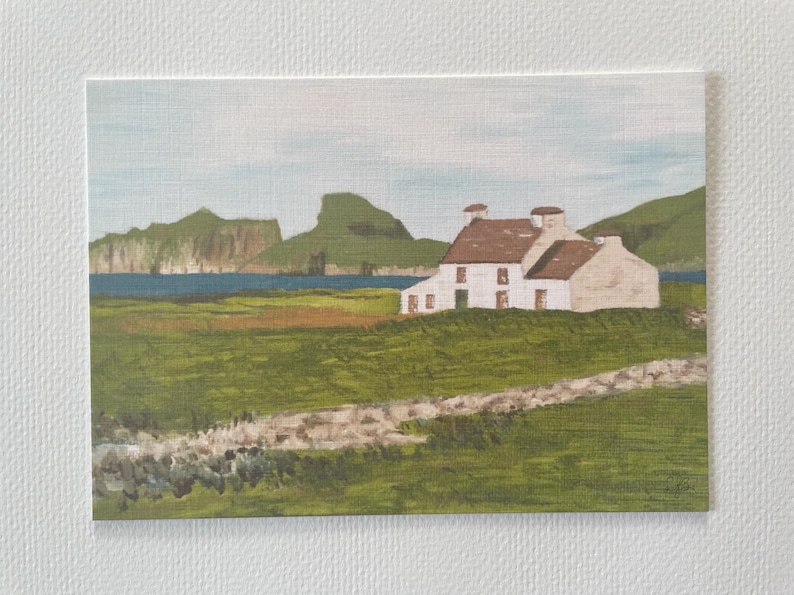 Puede incluir: Pintura de paisaje de una casa blanca con tejado marr&oacute;n, sobre un fondo de colinas verdes y un mar azul. Un muro de piedra recorre el primer plano, con un cielo azul claro. La obra est&aacute; enmarcada.