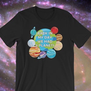 May include: Black t-shirt with a colorful graphic of planets and the text "BACK IN MY DAY WE HAD 9 PLANETS". The planets are depicted in various colors and designs, set against a space-themed background.
