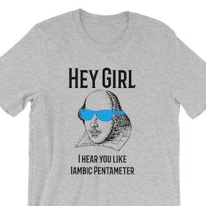 May include: A gray t-shirt with a black and white illustration of William Shakespeare wearing blue sunglasses. The text "HEY GIRL" and "I HEAR YOU LIKE IAMBIC PENTAMETER" is printed on the shirt.