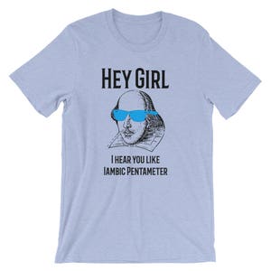 May include: A light blue t-shirt with a black graphic of William Shakespeare wearing blue sunglasses. The text "Hey Girl" and "I hear you like Iambic Pentameter" is printed on the shirt.