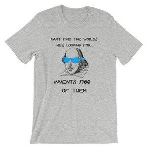 May include: A gray t-shirt with a black and white illustration of William Shakespeare wearing blue sunglasses. The text on the shirt reads "Can't find the words he's looking for. Invents 1700 of them."
