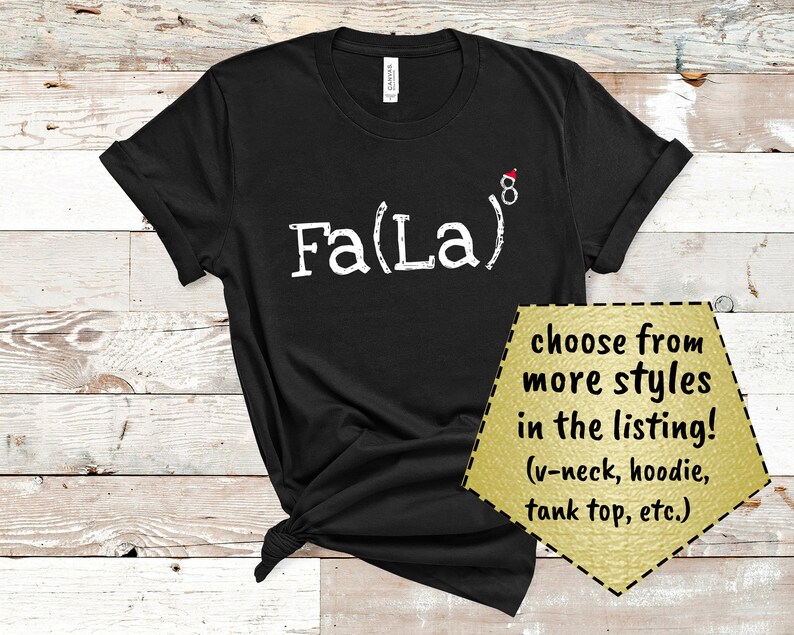 May include: Black t-shirt with white text that reads "Fa(La)8" with a small red Santa hat on the 8. The text has a distressed look.  The t-shirt is shown on a wood background.  Choose from more styles in the listing! (v-neck, hoodie, tank top, etc.)