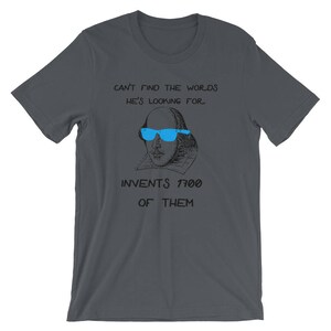 May include: A dark gray t-shirt with a black and white illustration of William Shakespeare wearing blue sunglasses. The text "Can't find the words he's looking for. Invents 1700 of them." is printed on the shirt.