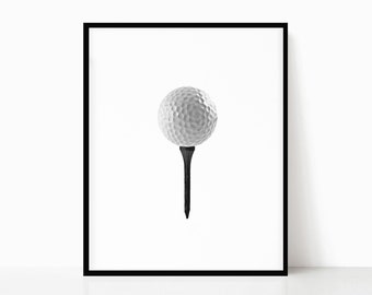 Op de afbeelding: Een witte golfbal op een zwarte tee, geïsoleerd op een witte achtergrond.