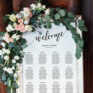 Puede incluir: Un plano de asientos de boda blanco con texto negro. El plano enumera las mesas del 1 al 12 con los nombres de los invitados para cada mesa. El plano está titulado "Bienvenido Sarah & Jacob 15 de marzo de 2019".