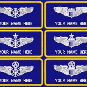 May include: Six rectangular blue embroidered patches with yellow borders. Each patch features white stitched wings and a central emblem, with the text YOUR NAME HERE embroidered in white at the bottom of each individual patch design.