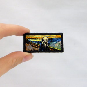May include: Embroidered patch featuring Edvard Munch's "The Scream" artwork. The patch depicts a figure with hands on its face against a backdrop of a vibrant sky and water. The patch is rectangular with a black border.