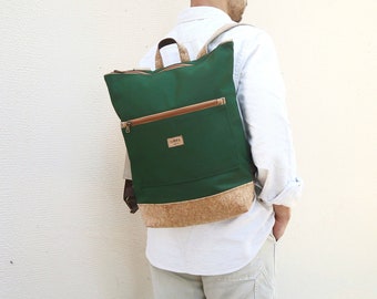 Könnte beinhalten: Ein grüner Canvas-Rucksack mit Korkboden und braunem Reißverschluss. Der Rucksack hat eine kleine Tasche auf der Vorderseite mit einem braunen Reißverschluss.
