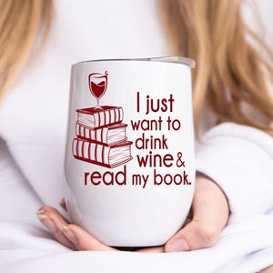 Op de afbeelding: Witte geïsoleerde wijntumbler met een rode afbeelding van een wijnglas bovenop een stapel boeken. De tekst "I just want to drink wine & read my book" is in het rood op de tumbler gedrukt.