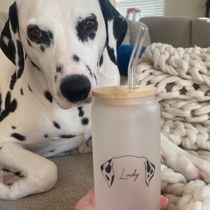 May include: A frosted glass water bottle with a bamboo lid and a black and white dog silhouette with the name "Lucky" printed on it. The bottle has a clear glass straw.
