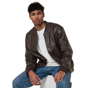 May include: A brown faux leather bomber jacket with a zipper closure and a small logo on the left chest. The jacket has a ribbed collar, cuffs, and waistband.