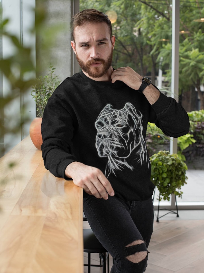 Op de afbeelding: Een zwart sweatshirt met een witte afbeelding van een hondenkop. De hondenkop is gestileerd met lijnen en lijkt een Cane Corso te zijn.