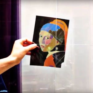 May include: A close-up of a painting of a woman with a blue and orange turban, a pearl earring, and a red and orange dress. The painting is on a white background.