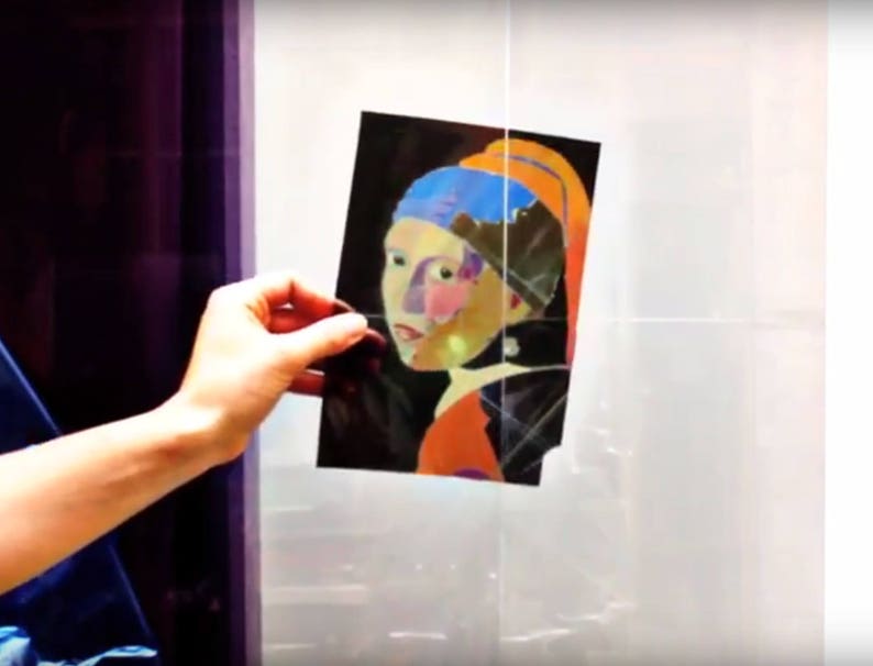 May include: A close-up of a painting of a woman with a blue and orange turban, a pearl earring, and a red and orange dress. The painting is on a white background.